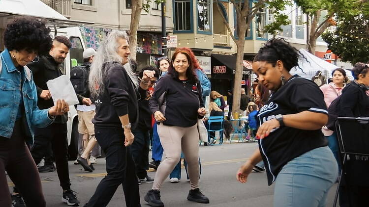 A wide shot of people dancing in a street during an outdoor event.