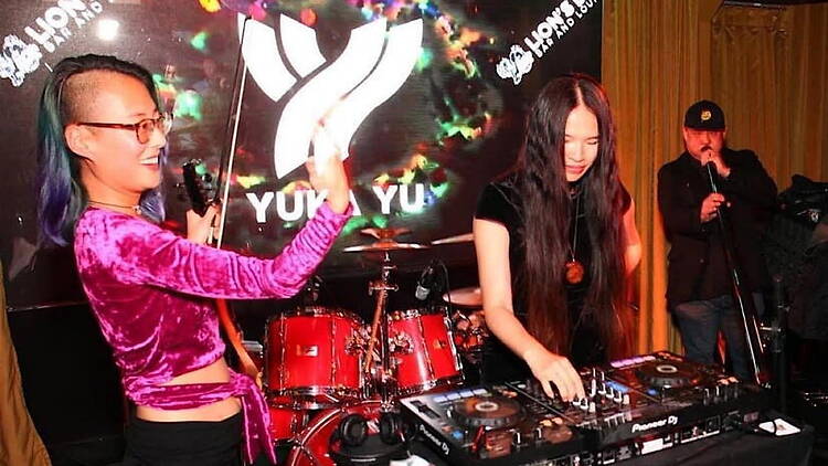 A wide shot of a DJ performing at a mixing console on stage.
