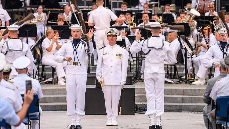 A wide shot of sailors standing before a military band during a ceremony