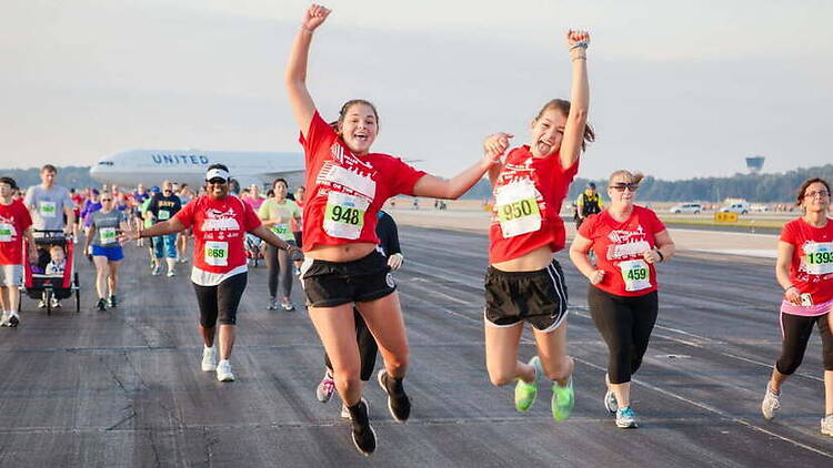 A wide shot of runners celebrating during a race on an airport runway. A wide shot of runners celebrating during a race on an airport runway.