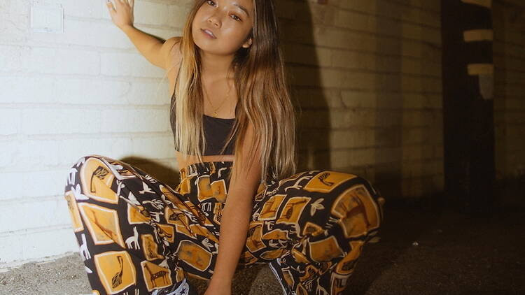 Woman posing in patterned pants against a brick wall indoors. Woman posing in patterned pants against a brick wall indoors.