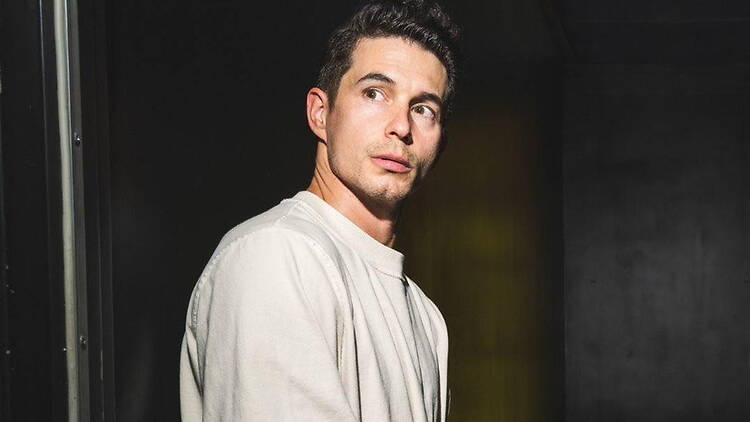 A close-up of a person looking to the side in a dark room.