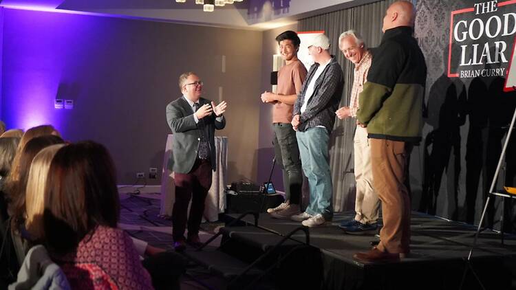 A wide shot of five people on stage during a live magic show A wide shot of five people on stage during a live magic show