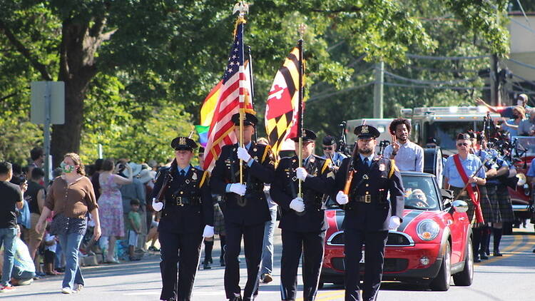 A wide shot of a parade procession with uniformed people carrying flags on a street A wide shot of a parade procession with uniformed people carrying flags on a street