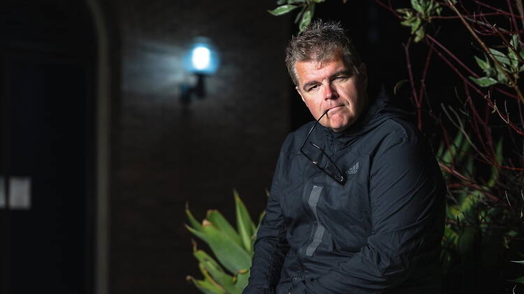 Close-up of a person sitting outdoors beside plants at night Close-up of a person sitting outdoors beside plants at night