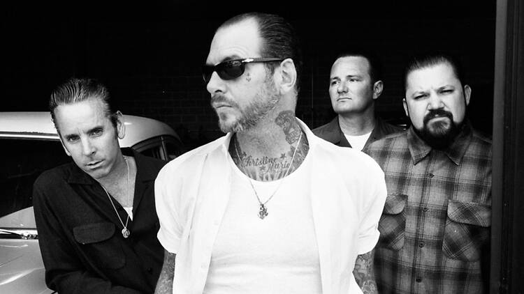 A wide shot of four people posing together in a black-and-white photo.