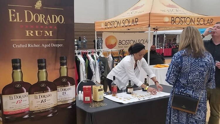 A wide shot of people sampling drinks at a beverage booth during an event.