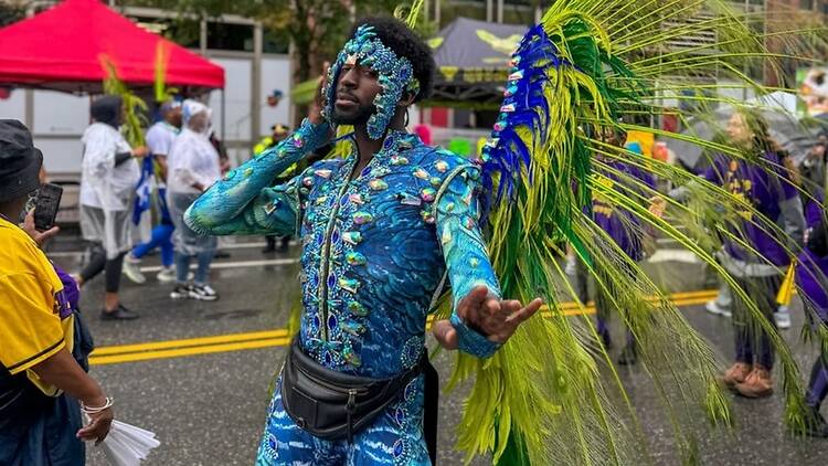 A wide shot of a person in a vibrant costume dancing in a street parade.