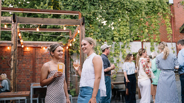 Two women enjoying beer in a warmly lit brewery courtyard.