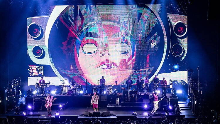 A wide shot of a band performing on stage under colorful lights. A wide shot of a band performing on stage under colorful lights.