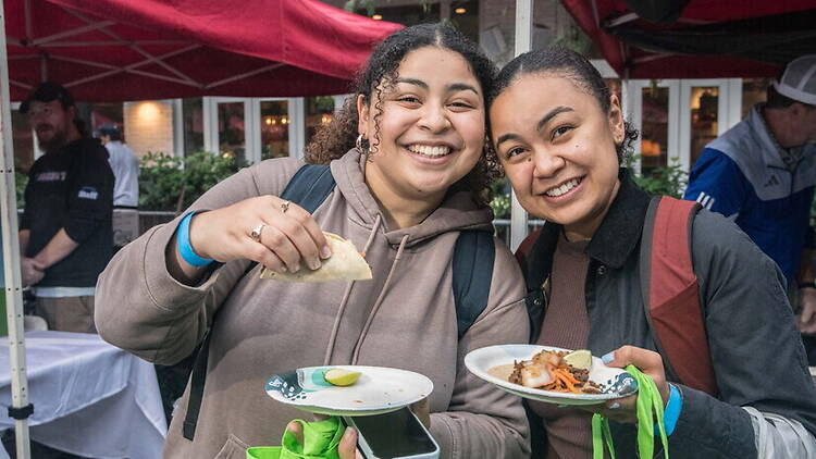 Close-up of two people holding plates of food at an outdoor community event