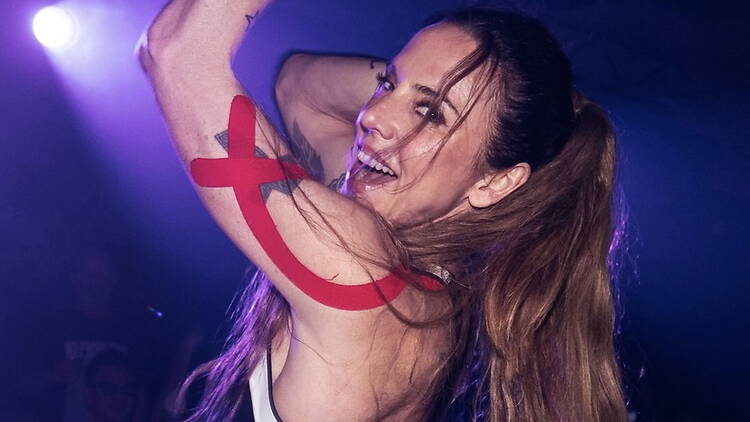 Close-up of a performer raising an arm while dancing under stage lights