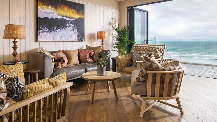 The Living Space snug view at Watergate Bay Hotel showing a sofa and chairs with the sea in the background