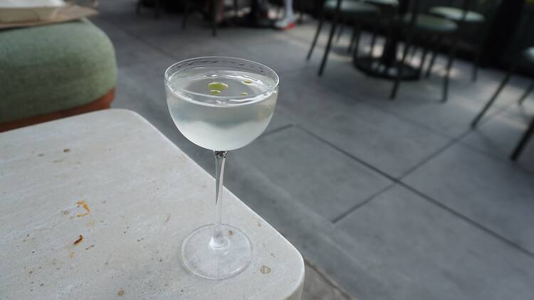 A clear cocktail in a coupe glass on white table