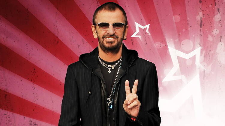 A close-up of a person smiling and holding up a peace sign against a red star backdrop. A close-up of a person smiling and holding up a peace sign against a red star backdrop.