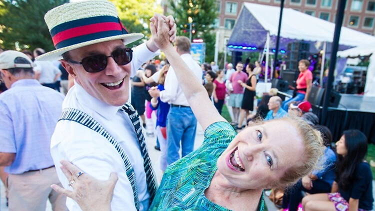 Close-up of two people dancing near a stage at an outdoor community event Close-up of two people dancing near a stage at an outdoor community event