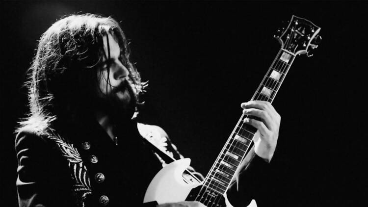 Close-up of a musician playing an electric guitar on a dark stage Close-up of a musician playing an electric guitar on a dark stage