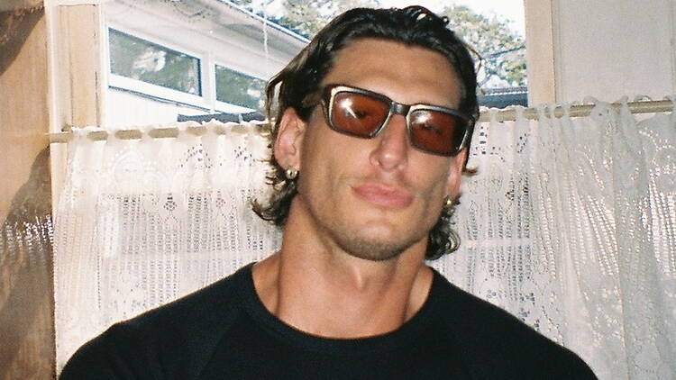 A close-up of a person wearing sunglasses and a black shirt indoors. A close-up of a person wearing sunglasses and a black shirt indoors.