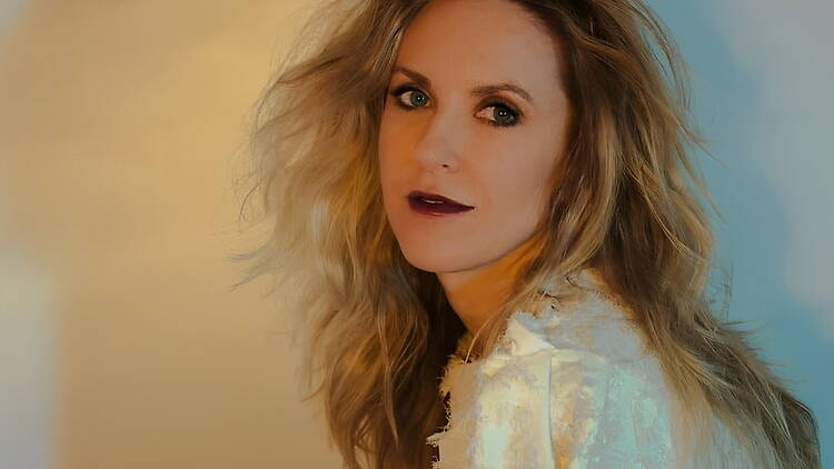 Close-up of a person posing indoors against a softly lit backdrop Close-up of a person posing indoors against a softly lit backdrop