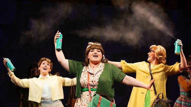 A wide shot of performers raising cans and singing on stage. A wide shot of performers raising cans and singing on stage.
