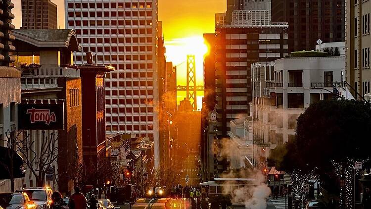 A wide shot of a city street at sunset with a bridge in the background. A wide shot of a city street at sunset with a bridge in the background.