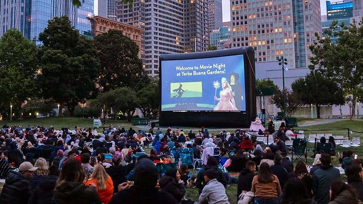 A wide shot of a crowd watching an outdoor movie screening at Yerba Buena Gardens. A wide shot of a crowd watching an outdoor movie screening at Yerba Buena Gardens.