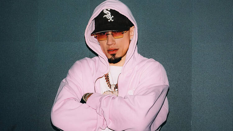 Front view of a person in a pink hoodie standing with arms crossed in front of a digital screen. Front view of a person in a pink hoodie standing with arms crossed in front of a digital screen.