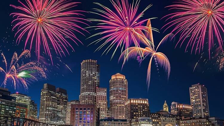 A wide shot of fireworks lighting up a city skyline at night. A wide shot of fireworks lighting up a city skyline at night.