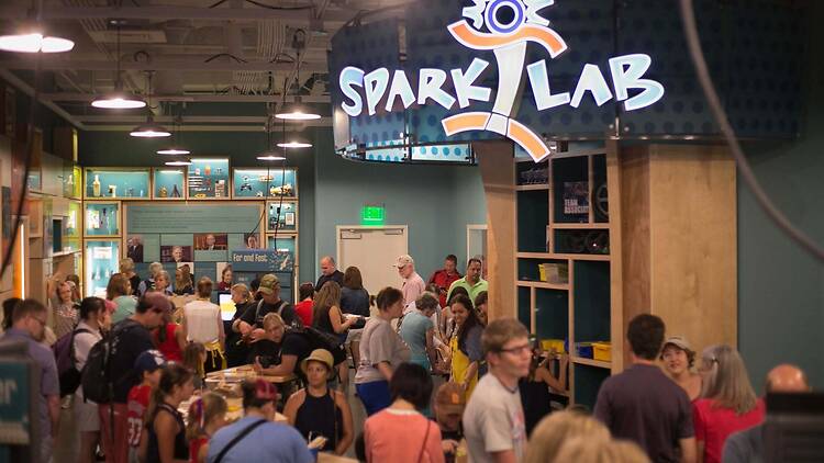 A wide shot of people exploring exhibits and activities at the Spark Lab museum.