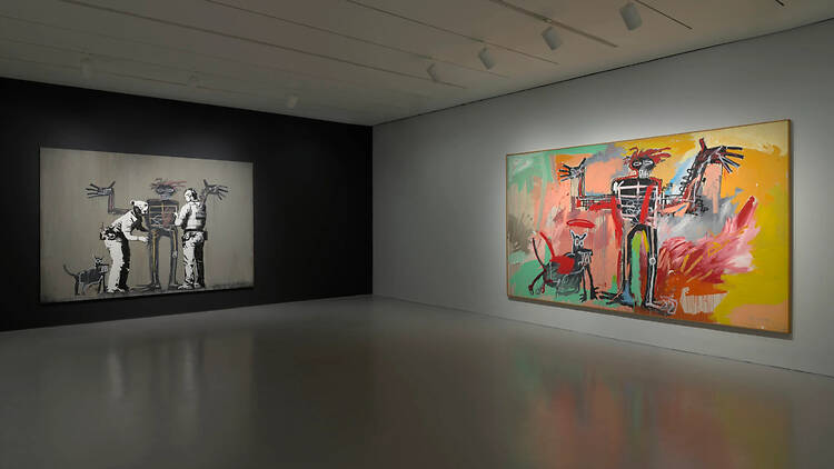 A wide shot of two large paintings displayed in a modern art gallery. A wide shot of two large paintings displayed in a modern art gallery.