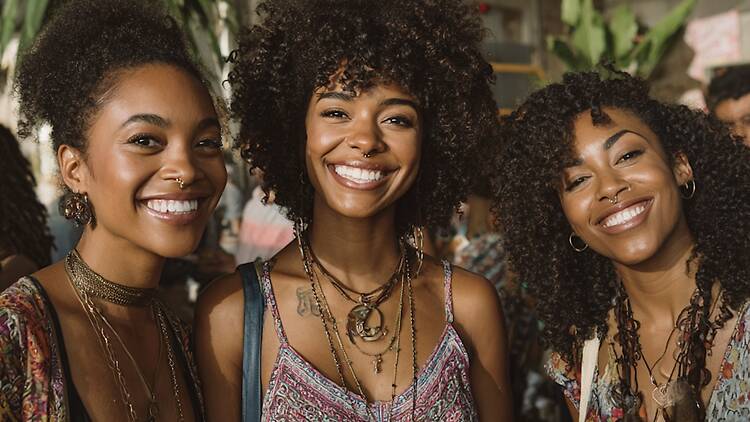 A close-up of three people smiling and posing together at an indoor event. A close-up of three people smiling and posing together at an indoor event.