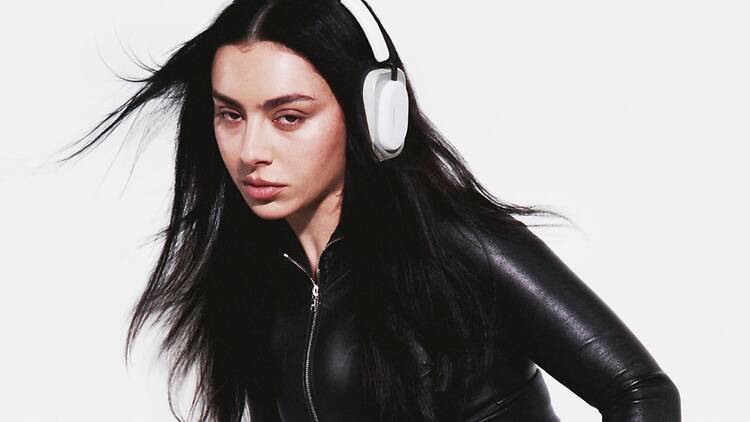 A medium shot of a person wearing white headphones and a black outfit against a white backdrop. A medium shot of a person wearing white headphones and a black outfit against a white backdrop.