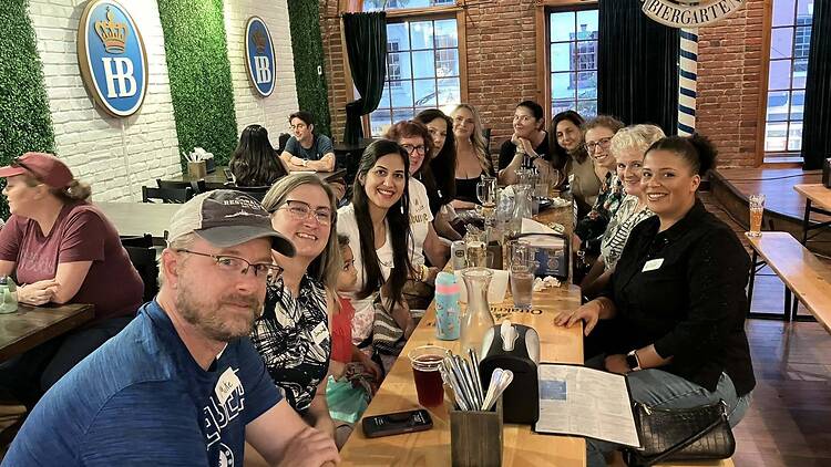 Wide group photo of people gathered around a table at a restaurant. Wide group photo of people gathered around a table at a restaurant.