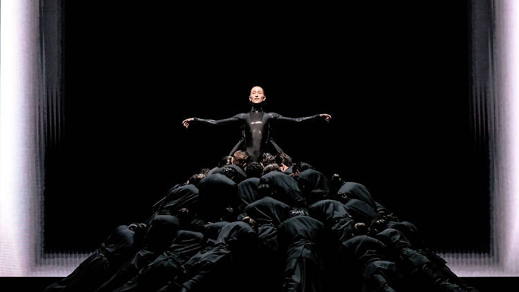 A futuristic scene with dancers dressed in all black costumes in Mere Mortals 