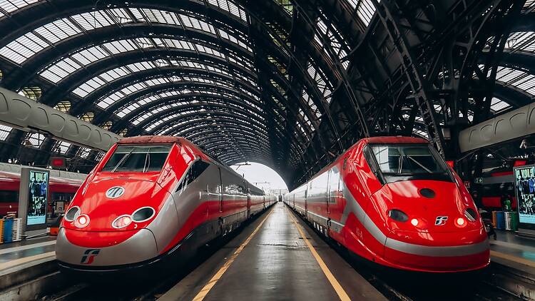 Two symmetrically situated FrecciaRossa trains at a station in Milan