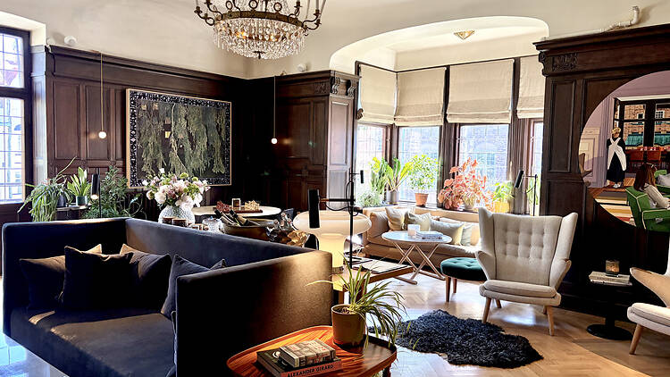 Alt text: Elegantly furnished hotel lounge with dark wood paneling, parquet floors, plush sofas, and a chandelier at Ett Hem in Östermalm.