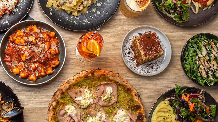 A table laden with pizza and pasta.