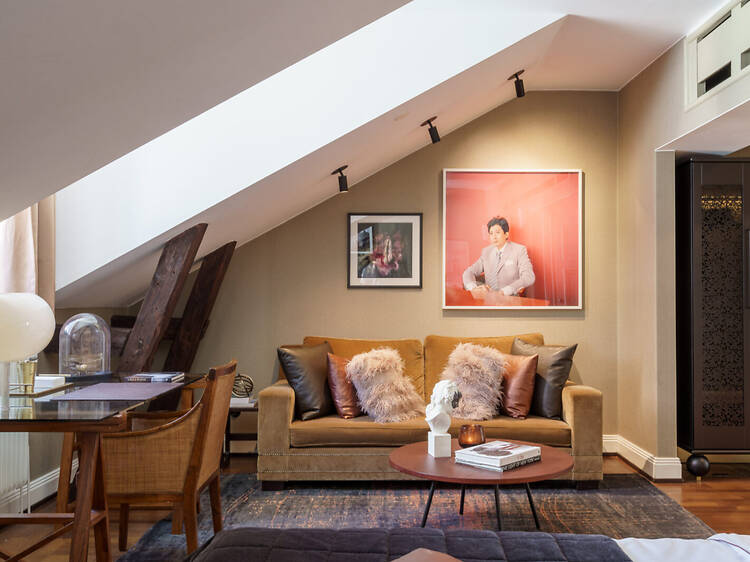 Lydmar Hotel Luxury Attic Suite in Central Stockholm Stylish attic lounge area at Lydmar Hotel in Stockholm with sloped ceilings, plush sofa, framed artwork, and modern Scandinavian decor.