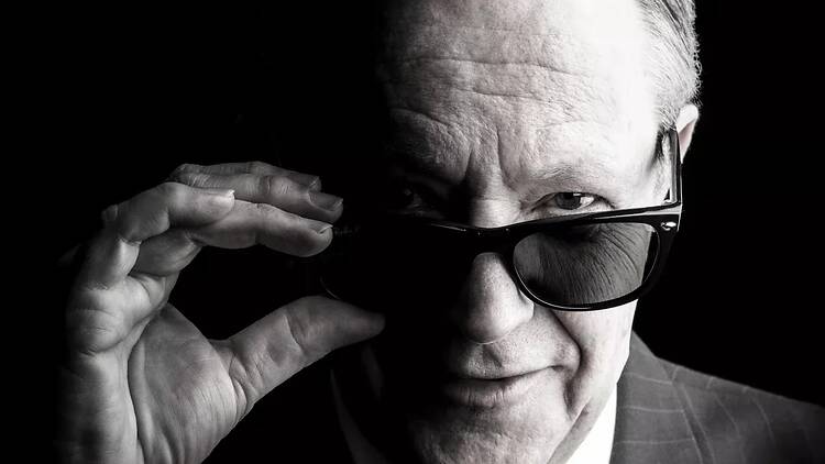 black and white photo of man in suit peering over sunglasses