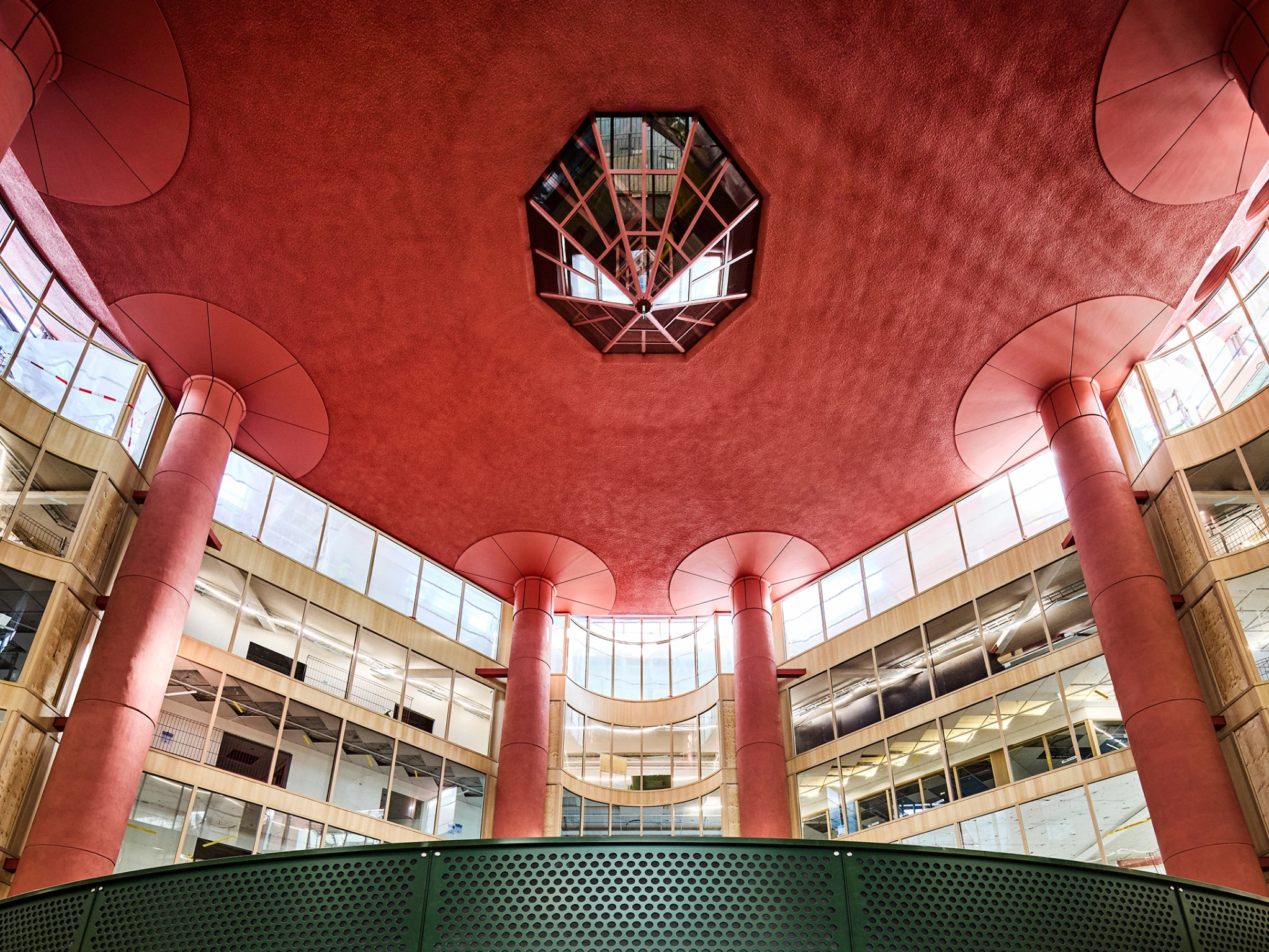 The red ceiling of S&ouml;derhallarna seen from below, with flared columns, an octagonal skylight and curved tiers of wood-framed glazing.