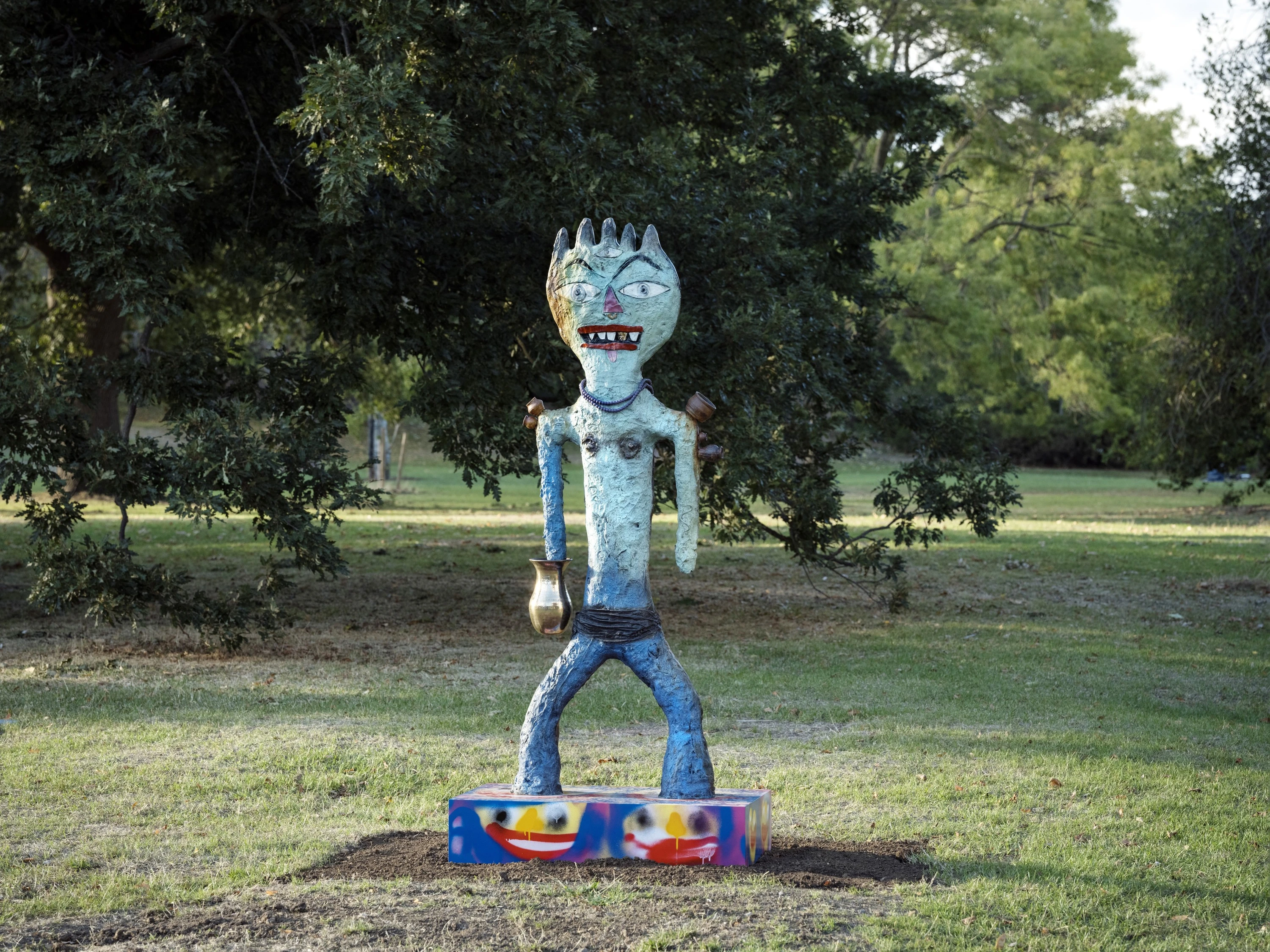 Blue bronze sculpture of a warrior figure on a colourful plinth 