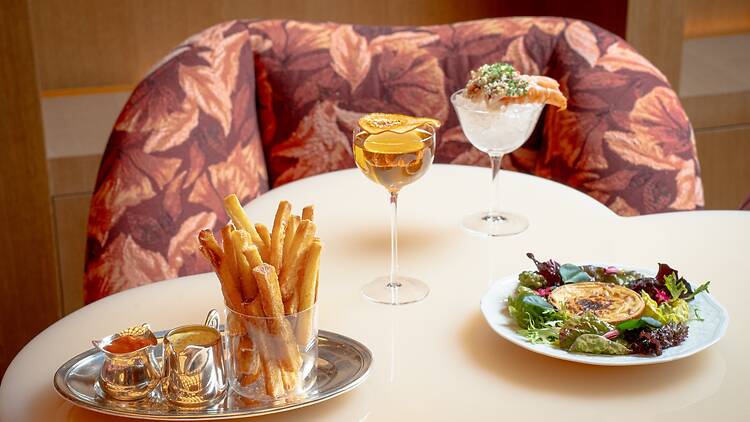 Two cocktails and fries and a salad on a table