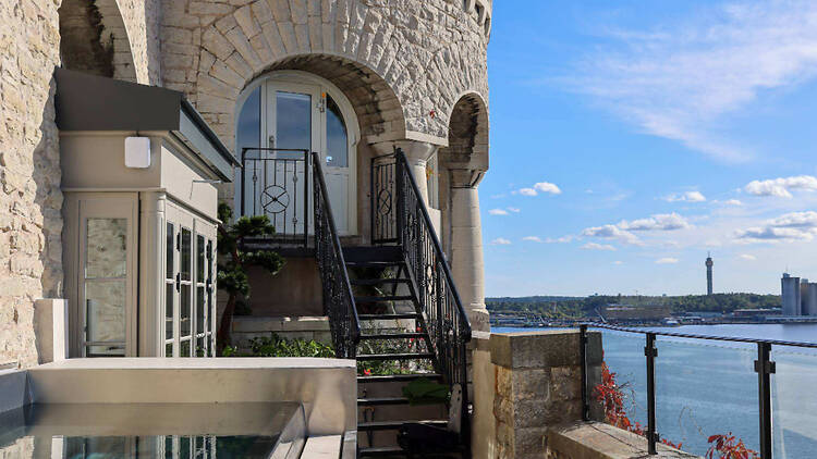 Outdoor Pool Terrace at Aqua di Foresta Roman Spa, Lidingö An outdoor pool on a stone terrace with wrought-iron stairs against a castle-like facade overlooking the sea in Lidingö, Stockholm