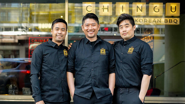 Stockholm, Slussen, Chingu Three men in black Chingu shirts outside the restaurant, beneath gold Chingu Korean BBQ signage.