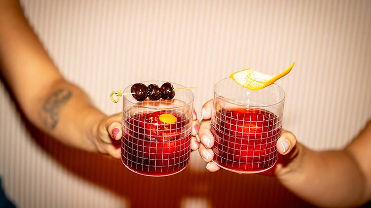 Two people holding negronis