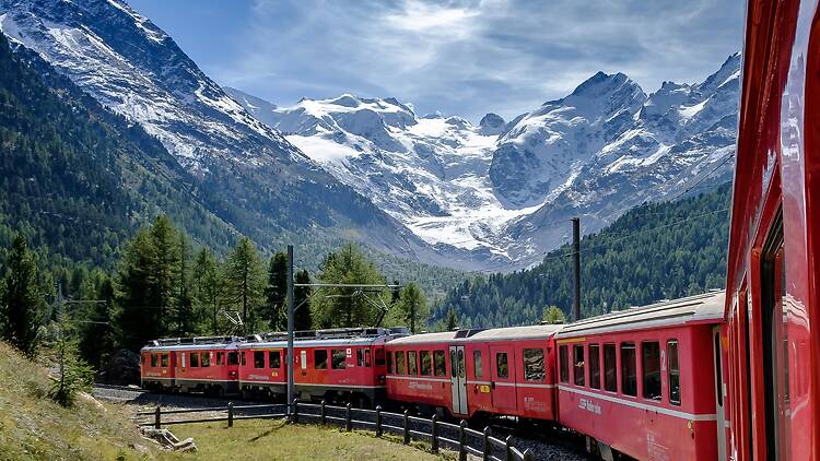 The Bernina Express Train on tracks near alpine mountain
