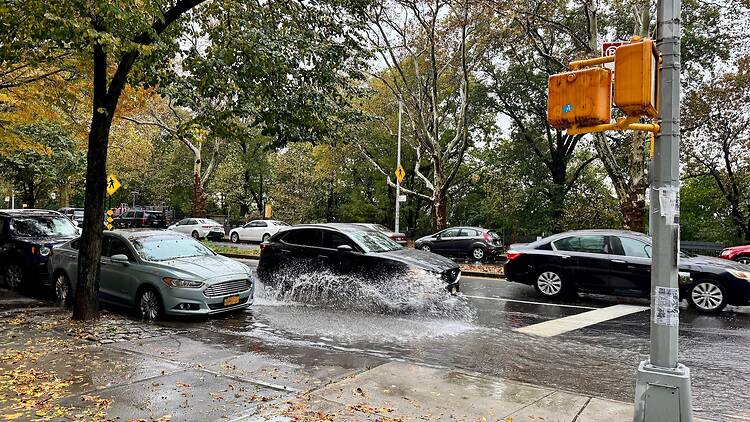Car splashing water while driving through flooded section of Riverside Drive