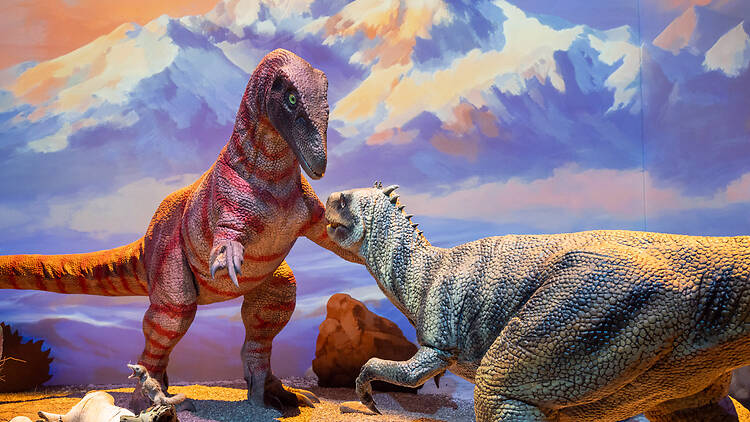 Dinosaurukset taistelevat taustallaan terävähuippuiset vuoret maalauksessa Dinosaurukset taistelevat taustallaan terävähuippuiset vuoret maalauksessa