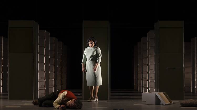 A woman looking down at Weizenbaum, who is huddled on stage