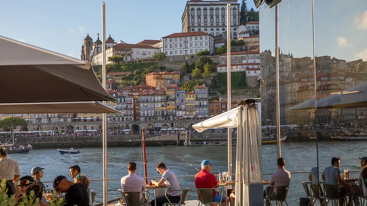 People at a restaurant in Vila Nova de Gaia with Ribeira, Porto old town embankment on the Douro River as background People at a restaurant in Vila Nova de Gaia with Ribeira, Porto old town embankment on the Douro River as background